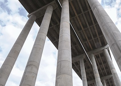 Close up of three bridge columns from below, looking up at bridge structure