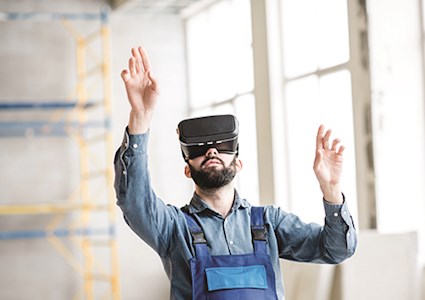 Construction worker in bib reaching out to virtual objects he sees in his VR goggles