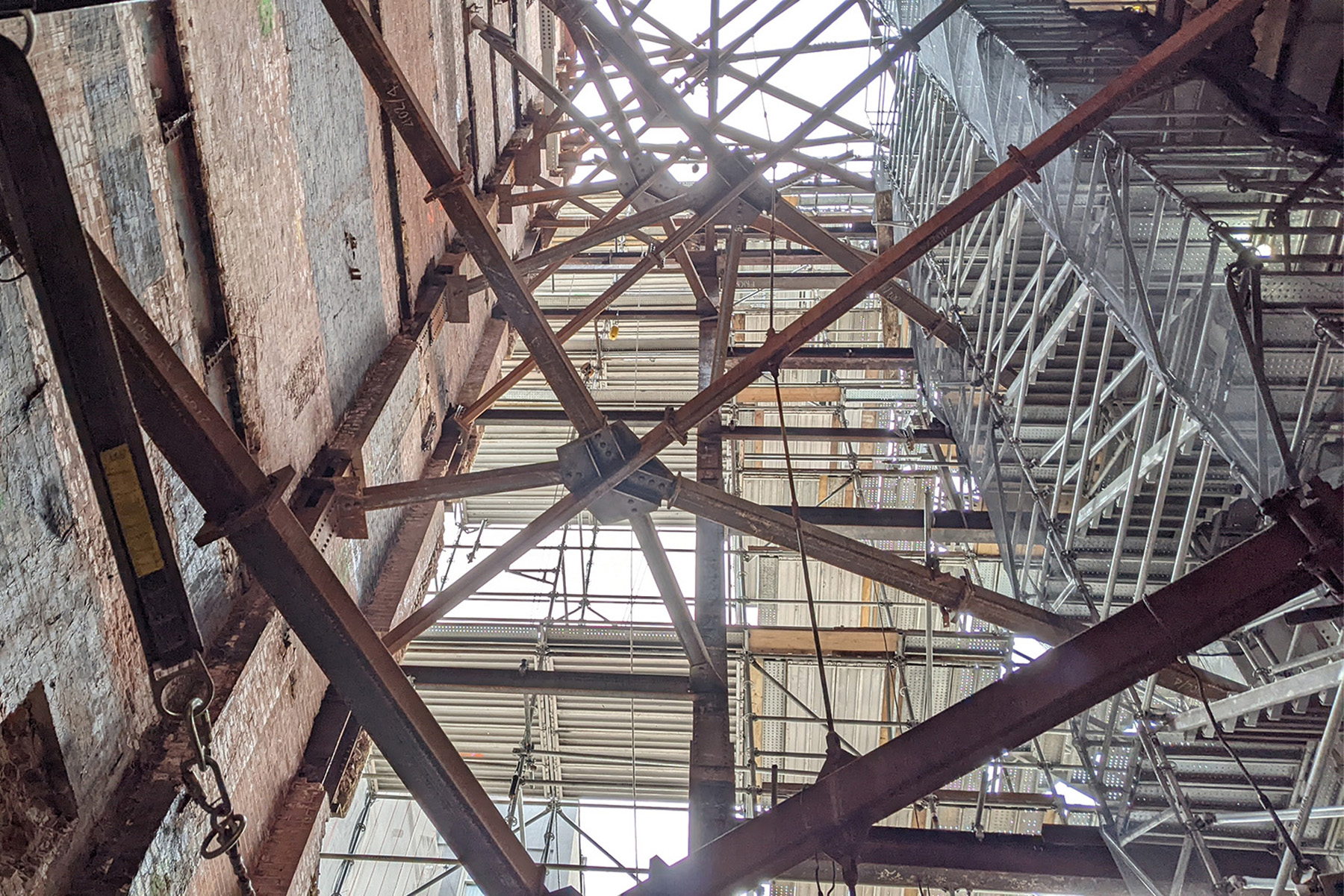 A temporary vertical braced frame and temporary shoring near a shear wall at a construction site. 