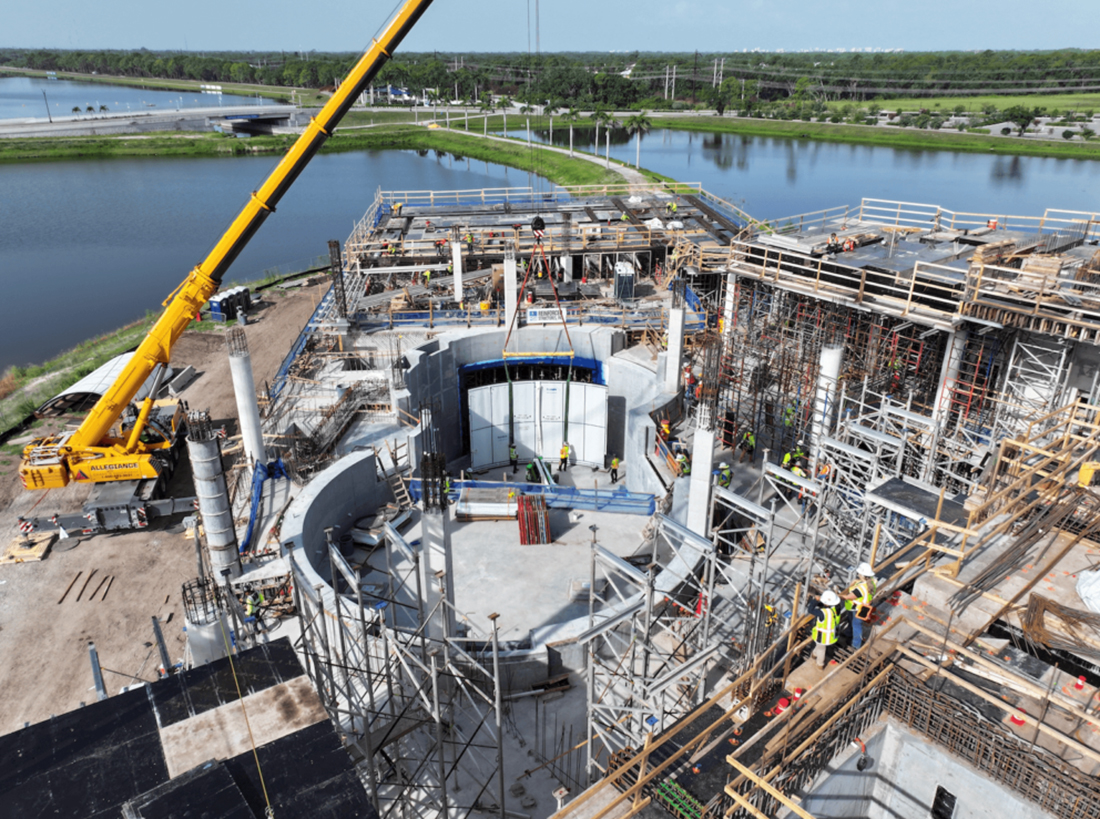 Aerial view of aquarium construction site with circular tanks, scaffolding, and crane
