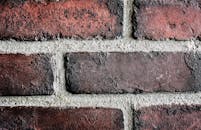 Detailed close-up of a textured red brick wall with visible mortar lines, emphasizing texture and structure.